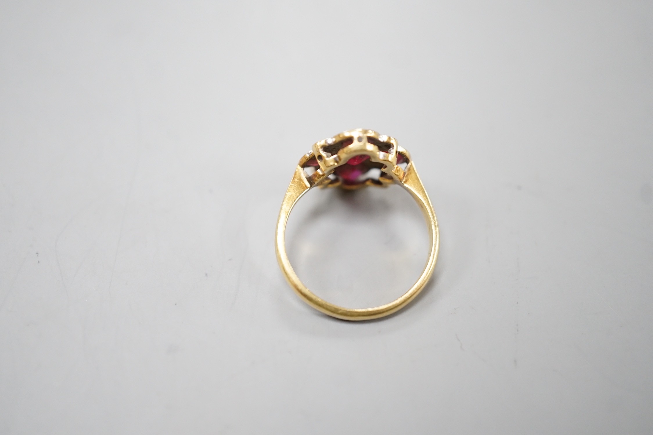 A 1920's 18ct and plat and five stone ruby set quatrefoil shaped ring, with diamond chip spacers, size L, gross weight 3.5 grams.